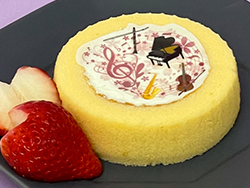 ピアノや音符のイラストを可食インクでプリントした白色可食シートをロールケーキの生クリーにのせてプリントケーキにしました。