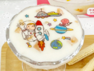 ロケットや宇宙船のイラストを透明の可食シートに印刷してた、プリント可食シートを牛乳と混ぜるだけで手軽に作れるスイーツにのせました